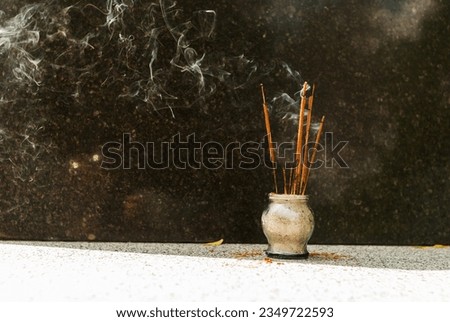 Smoking incense sticks in a glass vase. Festive incense near the marble Buddha statue. An offering to the gods. Aromatherapy. Expansion of consciousness. Meditation in Eastern religions.