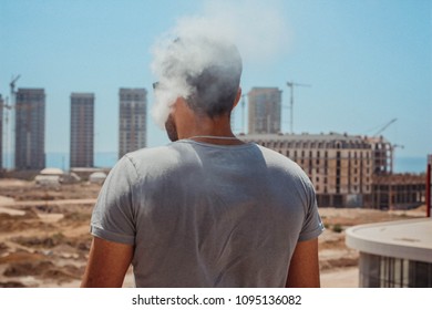 The smoking man on a roof looks on the city. - Powered by Shutterstock