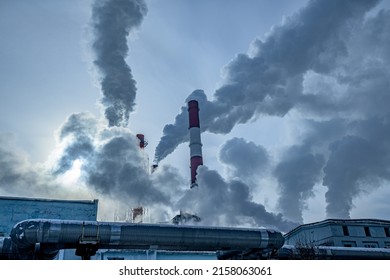 Smoking pipes of a thermal power plant in an industrial area of the city on a sunny frosty winter day