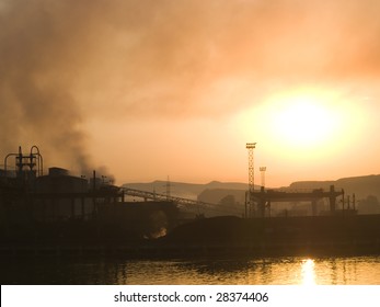 Smoking plant near a river at sunset