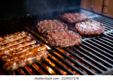 Smoky hamburger meat grilling for burgers. Fry on an open fire on the grill - bbq.Burgers and sausages Cooking Over Flames On The Grill. - Shutterstock ID 2129257178