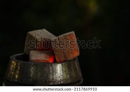 Smoldering embers in kaloud on hookah. Hookah smoking concept. Kalaud, charcoal tongs on hookah plate stands in nature.