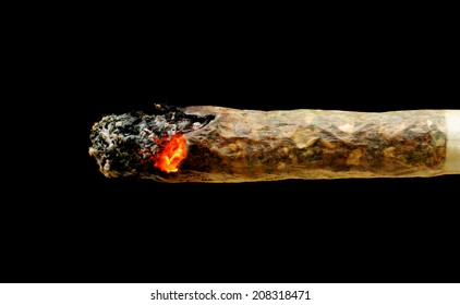 Smoldering marijuana joint isolated on black background