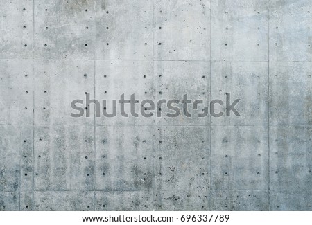 Smooth bare concrete wall with many concrete form dimples and grid lines.