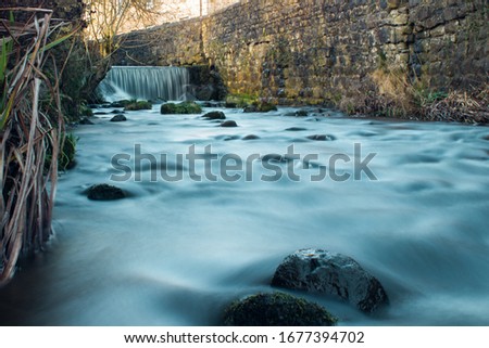 Smooth flowing stream with a waterfall in the backround. Ribble Valley.