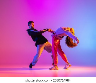 Smooth Movements. Two Young People, Guy And Girl, Dancing Contemporary Dance Over Pink Background In Neon Light. Modern Dance Aesthetics Concept