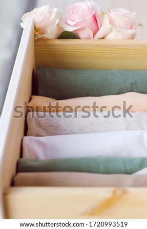a smooth, neat row of vertically folded clothes in natural, muted colors in a drawer, decorated with roses