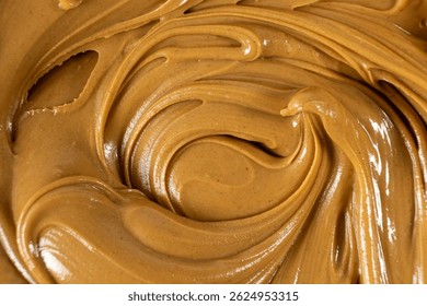 Remolino de mantequilla de nuez suave como fondo culinario.