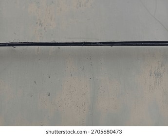 A smooth, reflective, and slightly textured surface (like metal or glass) in a muted greysilver tone, bisected by a sharp, thin black line
