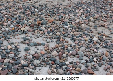 Smooth River Rocks Resting On The Sand And Dock.