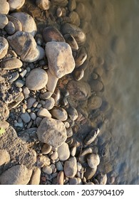 Smooth River Rocks Sitting Against The River Edge. 