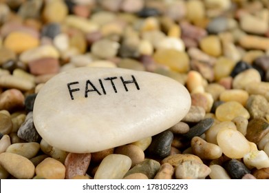 A smooth river stone is etched with the word faith for spiritual affirmation purposes. - Shutterstock ID 1781052293