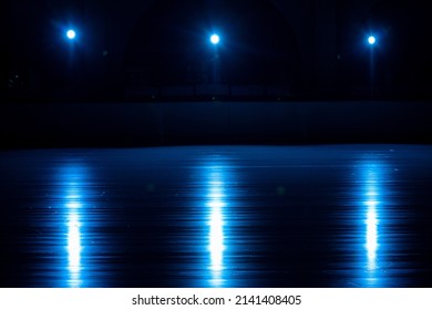 Smooth, Shiny Surface Of An Ice Rink With Reflected By Spotlights. Dark Empty Ice Arena With Soft Blue Light. Concept Of Winter Sports Games, Hockey, Figure Skating. Close Up.