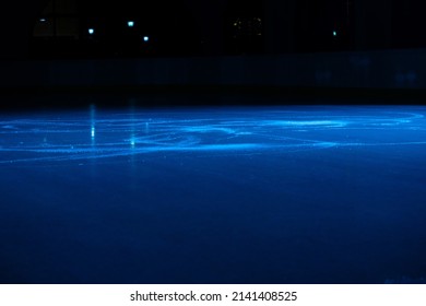 Smooth, Shiny Surface Of An Ice Rink With Reflected By Spotlights. Dark Empty Ice Arena With Soft Blue Light. Concept Of Winter Sports Games, Hockey, Figure Skating. Icy Background Of Slippery Ice.