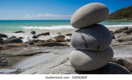Smooth Symbolic Oval Stones Delicately Stacked On Top of Each Other Also Known As Cairn Along the Coastline on a Clear Sunny Day at Granite Bay, Noosa National Park, Noosa Heads, Queensland, Australia
