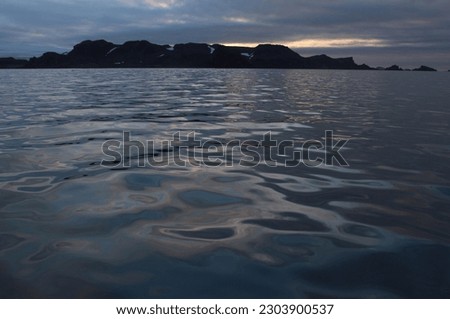 Smooth water surface in South ocean and rocks. Dark landscape