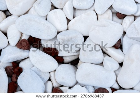 Smooth white pebbles intermingling with rough lava rock, creating a textured background for garden landscaping, zen elements, and natural patterns