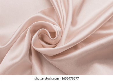 Smooth Wrinkled Silk Bedsheet, Fabric Background. Abstract Crumpled Satin Texture. Cream Color. Folded Cloth, Wallpaper. Soft Wavy Pastel Beige Material, Pink Glossy Textile.