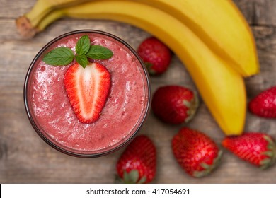 Smoothie With Banana And Strawberry In The Glass, Fresh Strawberries And Bananas On The Old Wooden Background