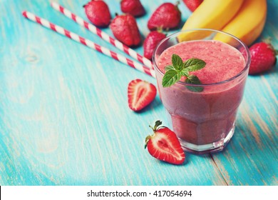 Smoothie With Banana And Strawberry In The Glass, Fresh Strawberries And Bananas On The  Wooden Background (toning)