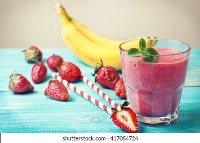 Smoothie With Banana And Strawberry In The Glass, Fresh Strawberries And Bananas On The  Wooden Background (toning)