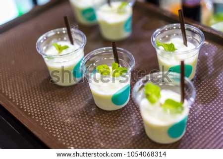 Smoothie beverage sample for refreshing concept in transparent tasting cup on brown tray. Marketing promotion for new launched flavor.