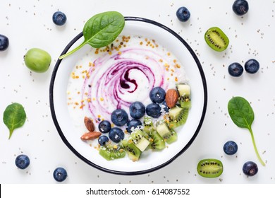 Smoothie Bowl With Acai Berry, Kiwi, Blueberries, Almonds, Coconut, Bee Pollen And Baby Spinach On White Background. Top View Of Healthy Detox Smoothy Bowl