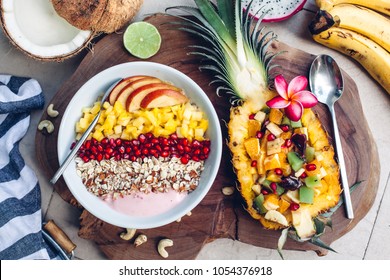 Smoothie bowl with colorful tropical fruits on wooden serving tray, top view from above. Summer healthy diet, vegan breakfast.