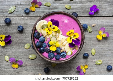 Smoothie bowl with fresh berries, nuts, seeds and flowers for healthy vegan vegetarian diet breakfast. top view - Powered by Shutterstock