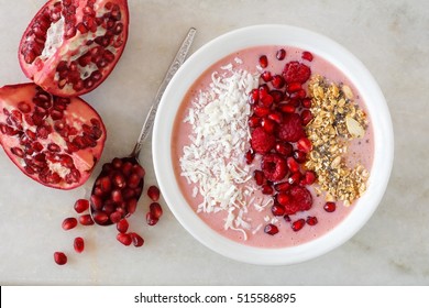 Smoothie Bowl With Pomegranates, Raspberries, Coconut And Granola, Overhead Scene On Marble