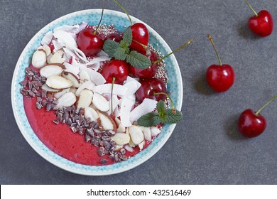 Smoothie bowl topped with cherry, coconut and almond