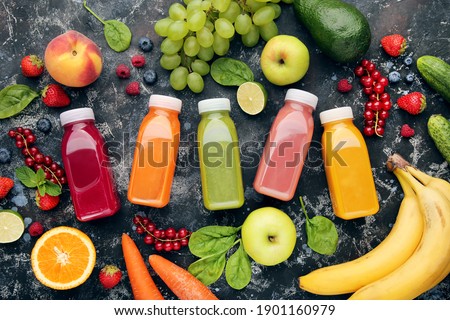 Smoothie in plastic bottles with fruits and vegetables on wooden background