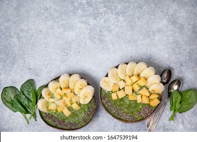 Smoothie Spinach Bowl With Banana And Mango, Chia Seeds In Coconut Bowls On A Gray Concrete Background. View From Above.