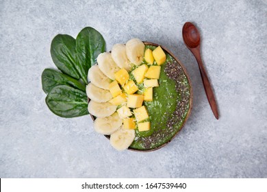 Smoothie Spinach Bowl With Banana And Mango, Chia Seeds In Coconut Bowls On A Gray Concrete Background. View From Above.