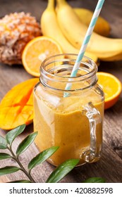 Smoothie With Tropical Fruits: Mango, Banana, Pineapple, Orange  In A Glass Jar Mason On The Old Wooden Background