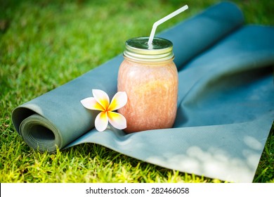 Smoothies and yoga mat on the grass