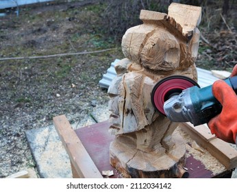 smoothing the texture surface of a wooden decorative product in the process of a carpenter working with solid wood outdoors, carving an owl from a wooden material for country style decor