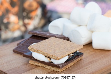 Smores Ingredients At A Beach Bonfire With Chocolate, Marshmellow, And Graham Crackers With Room For Copy