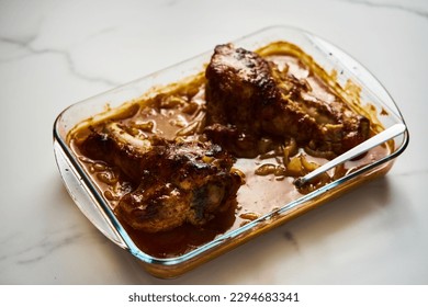 Smothered or stewed Turkey wings in a rectangular baking dish. Roasted to a crisp, the wings lie drowned in a thick gravy with vegetables. Food photo.