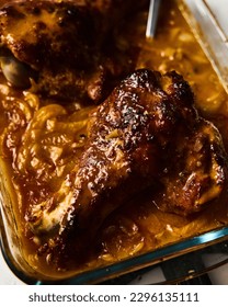 Smothered or stewed Turkey wings in a rectangular baking dish. Roasted to a crisp, the wings lie drowned in a thick gravy with vegetables. Food photo.