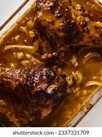 Smothered or stewed Turkey wings in a rectangular baking dish. Roasted to a crisp, the wings lie drowned in a thick gravy with vegetables. Food photo.