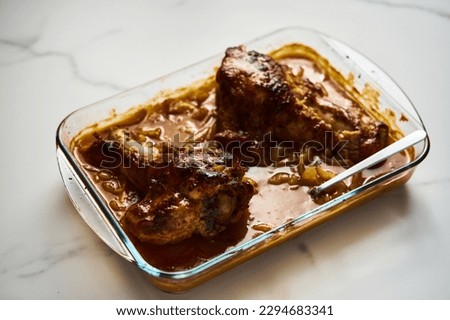 Smothered or stewed Turkey wings in a rectangular baking dish. Roasted to a crisp, the wings lie drowned in a thick gravy with vegetables. Food photo.