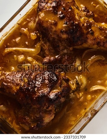 Smothered or stewed Turkey wings in a rectangular baking dish. Roasted to a crisp, the wings lie drowned in a thick gravy with vegetables. Food photo.