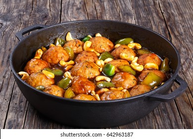 Smothering Tender Chinese Cashew Chicken Meatballs Tossed With Sauce Of Green Bell Pepper Chunks, Onion, Soy Sauce, Chinese Cooking Wine And Spices In Iron Saucepan, Close-up