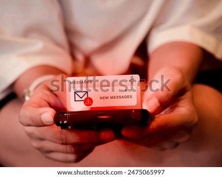 SMS spam and fake text message phishing concept. System hacked warning alert, email hack, scam malware spreading virus messages alert showing on mobile smart phone in woman's hands, dark red tone.