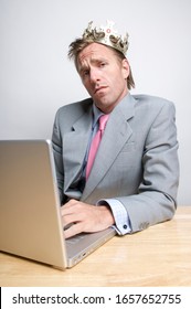 Smug Businessman Wearing Royal Gold Crown Sitting In Front Of His Laptop Computer