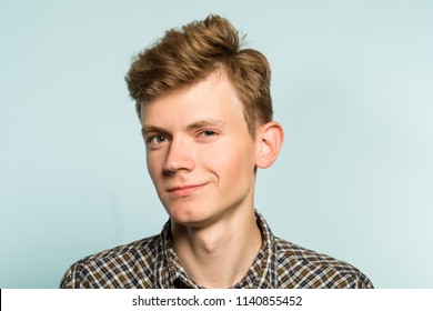 Smug Handsome Guy With A Mysterious Smile. Cute Geek Or Dork. Portrait Of A Young Guy On Light Background. Emotion Facial Expression. Feelings And People Reaction.