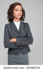 Smug Priggish Assured Successful Young Curly Business Woman In Gray Suit With Arms Crossed 