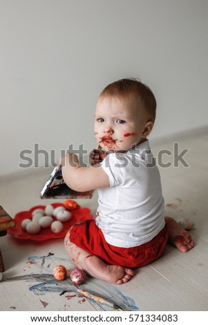 Smutty Kid Toddler With Watercolor Paints In Red Trousers On A Light Background Smutty Kid Toddler With Watercolor Paints In Red Trousers On A Light Background
