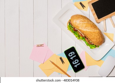 Snack at break time. Healthy business lunch in office, top view of Vietnamese sandwich, or Ban Mi on white wooden desk with coffee, mobile phone and notepad with pen flat lay.